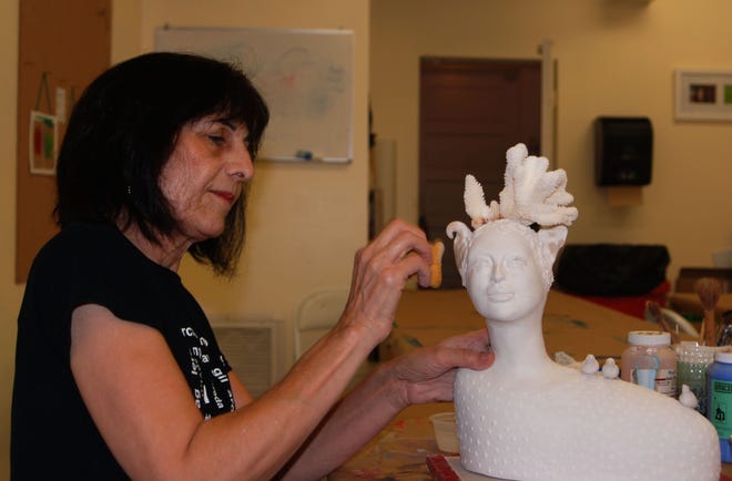 Sculptor Fay Samimi works on a clay piece of a woman with a coral hat at her studio in The Hub on Canal.
