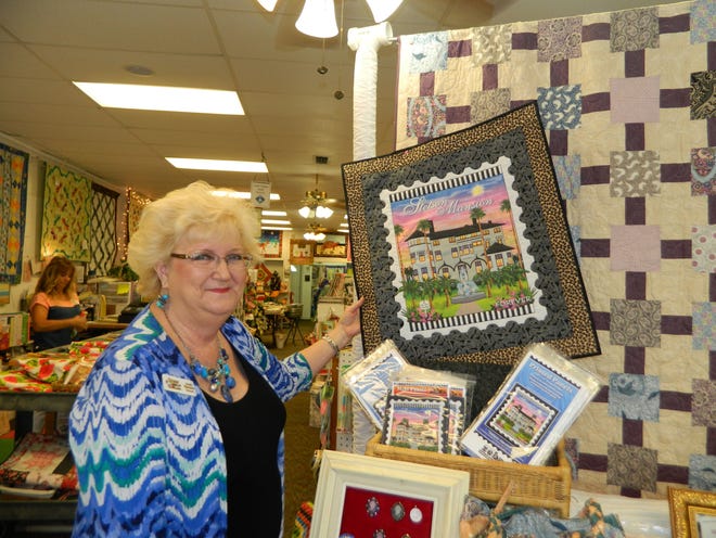 Judy Hansen holds up a Stetson Mansion-themed quilt at her shop in DeLand.