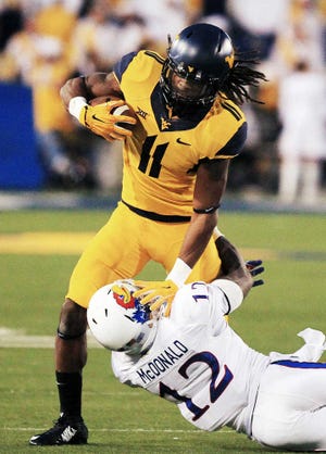 West Virginia's Kevin White (11) is tackled by Kansas' Dexter McDonald (12) during the third quarter of an NCAA college football game in Morgantown, W.Va., Saturday, Oct. 4, 2014. West Virginia won 33-14. (AP Photo/Chris Jackson)