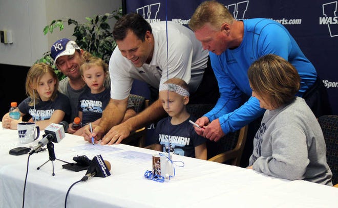Karis Selk, 7, sits at the center of the table surrounded by her family and Ron McHenry (left) the women's basketball coach and Chris Herron (right) the volleyball coach at Washburn University. Caroline Sweeney/Capital-Journal