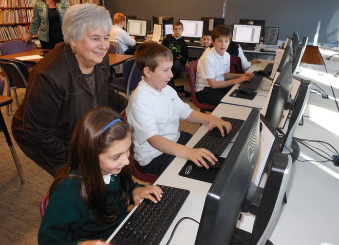 St. Francis De Sales Parochial School Principal Kathleen Coye visits with fifth-graders Emily Lyga and Jonathan Reese at the school's technology and media center room on Monday. Coye started as principal earlier this year. Telegram photo/Stephanie Sorrell-White