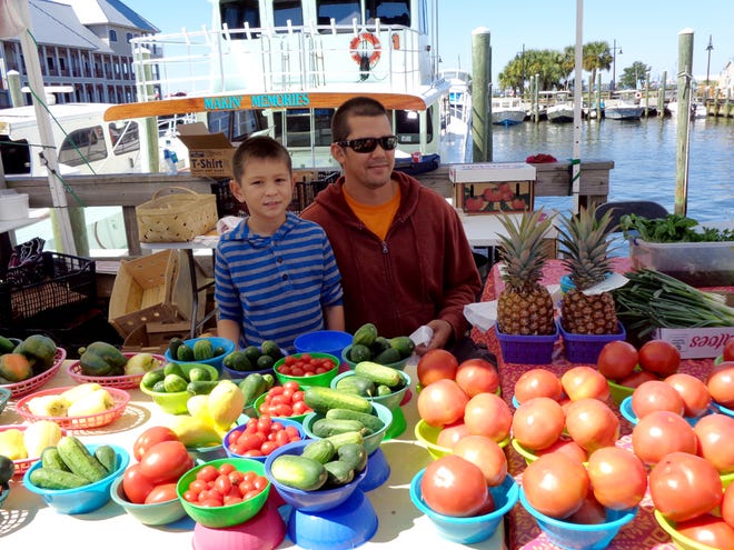 Ethan Weslowski, 8, helps his dad, James Weslowski, on Saturday during the St. Andrews Waterfront Farmers Market at Smiths’ Yacht Basin.