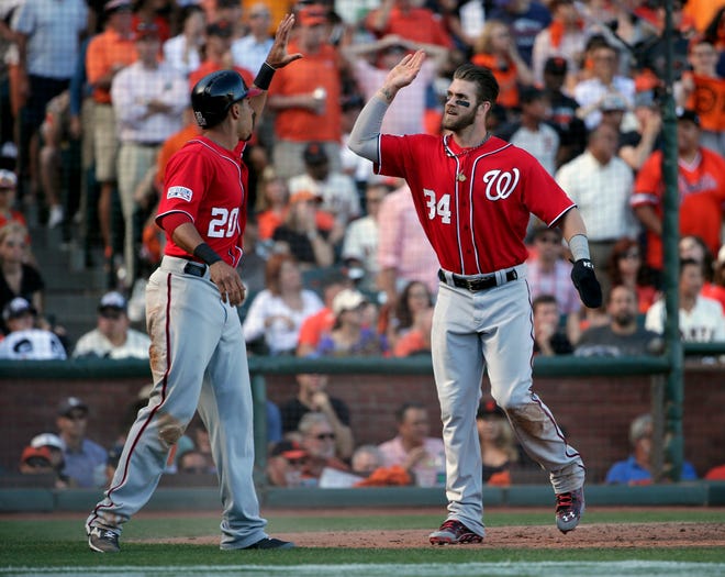 Washington Nationals Bryce Harper (34) high-fives Ian Desmond after they both scored in the seventh inning against the San Francisco Giants during Monday's Game 3 of the NLDS in San Francisco on Monday. The Nationals staved off elimination in the best-of-five series with a 4-1 win. AP photo
