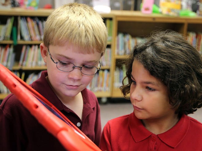 Fifth-graders Gabe Albritton, 10, and Lily Henderson, 10, use an iPad in the library at Hiland Park Elementary School recently.