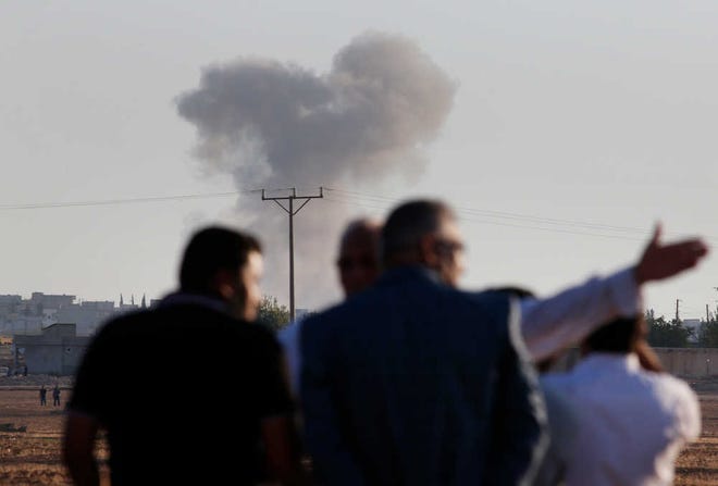 Turkish Kurds standing on the outskirts of Suruc, on the Turkey-Syria border, watch smoke rise following an airstrike in Kobani, Syria, where the fighting between militants of the Islamic State group and Kurdish forces intensified on Tuesday, Oct. 7, 2014. Kobani, also known as Ayn Arab, and its surrounding areas have been under attack since mid-September, with militants capturing dozens of nearby Kurdish villages.