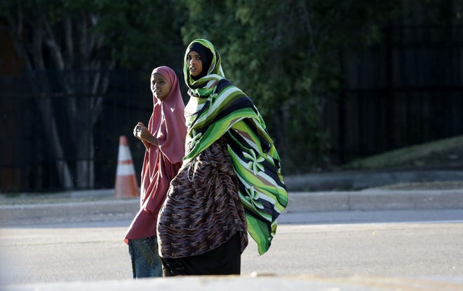 In this Oct. 3, 2014 file photo, two women glance at journalists gathered on a street next to an apartment complex where an Ebola infected man had stayed in Dallas.