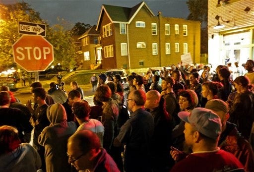 A crowd gathers near the scene in the 4100 block of Shaw Boulevard where a man was fatally shot by an off-duty St. Louis police officer on Wednesday, Oct. 8, 2014. St. Louis Police Lt. Col. Alfred Adkins said the 32-year-old officer was working a secondary security job late Wednesday when the shooting happened. (AP Photo/St. Louis Post-Dispatch, David Carson)