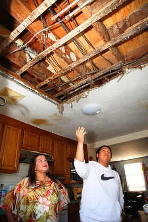 Stephanie Nguyen and her son Michael, 17, look at the collapsed kitchen ceiling in their Snug Harbor public housing apartment Wednesday, Oct. 8, 2014.