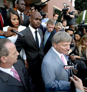 Minnesota Vikings running back Adrian Peterson, center, stands with his wife Ashley Brown Peterson, left, as they listen to Peterson's attorney Rusty Hardin, right, outside the courthouse after making his first court appearance Wednesday, Oct. 8, 2014, in Conroe, Texas. A Texas judge has tentatively set a Dec. 1 trial date for Peterson on a charge of felony child abuse for using a wooden switch to discipline his 4-year-old son. (AP Photo/David J. Phillip, Pool)