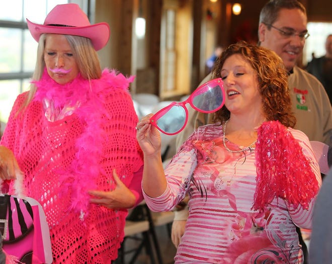 Georgie Johns and Michelle Gooding, both of New Philadelphia, have a laugh getting pinked out at the fifth annual Paint Tusc Pink kickoff at the Chamber business After Hours on Thursday at the Breitenbach Winery Tool Shed.