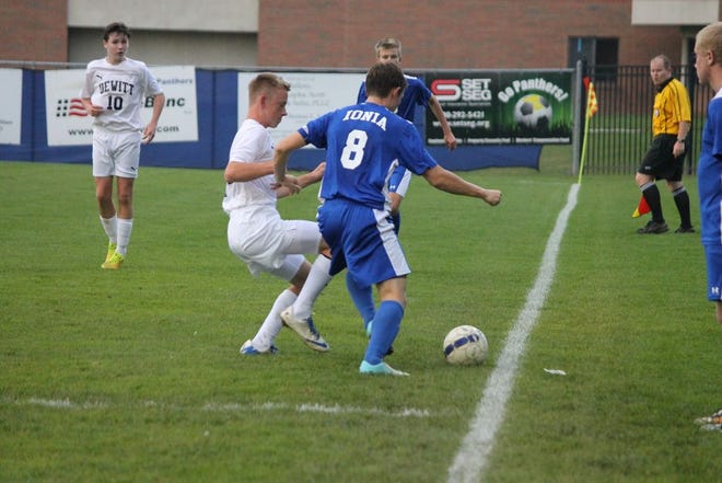 Ionia senior midfielder Christian Duell looks to kick the ball past the DeWitt player in an 8-0 mercy loss on Monday.