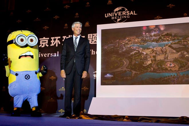 Tom Williams, chairman and chief executive officer of the Universal Parks and Resorts, stands next to a movie character called a Minion after he unveiled an artist's impression of the Universal Beijing theme park in Beijing.