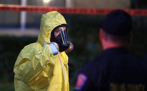 A hazmat worker looks up while finishing up cleaning outside an apartment building of a hospital worker, Sunday, Oct. 12, 2014, in Dallas. The Texas health care worker, who was in full protective gear when they provided hospital care for Ebola patient Thomas Eric Duncan, who later died, has tested positive for the virus and is in stable condition, health officials said Sunday. (AP Photo/LM Otero)