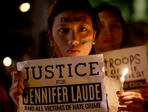 Protesters, mostly supporters of LGBT (Lesbians, Gays, Bisexuals and Transgenders), hold a lit candle and display messages to demand justice in the killing of a Filipino transgender Jeffrey "Jennifer" Laude, with a U.S. Marine as a possible suspect Tuesday, Oct. 14, 2014 in Manila, Philippines. Dozens of activists burned a mock U.S. flag as they protested at the U.S. Embassy in Manila on Tuesday, demanding that Washington hand over to the Philippines a U.S. Marine suspected in the killing of a transgender Filipino that the demonstrators labeled a hate crime.