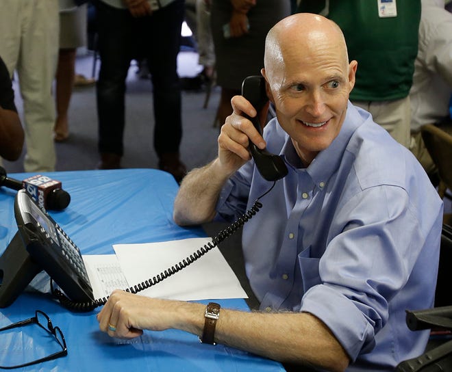 Florida Gov. Rick Scott makes a phone call to a voter at a campaign call center Thursday, Sept. 25, 2014, in Orlando, Fla.