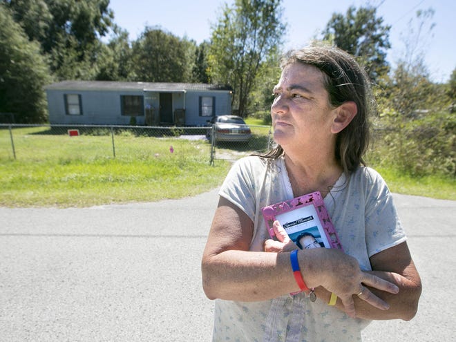 Theresa Fuller clutches a photo of her son Edward Moffitt outside his mobile home on Northwest 17th Place in Ocala on Wednesday.