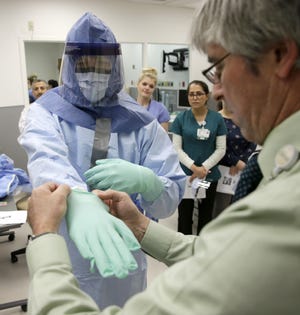 Registered nurses Keene Roadman (in personal protective equipment) and Fred Serafin demonstrate proper procedures during a training class Thursday, Oct. 16, 2014, at Rush University Medical Center in Chicago to doctors and nurses who are part of the core team that would treat Ebola patients.
