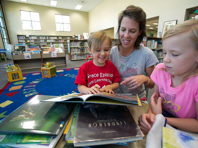 Garnet Pagh, 4, left, laughs and smiles as her mom Esther Pagh, center reads her a book as her sister Race Pagh, 8, right, listens as the three spent some time at the Marion County Public Library on East Silver Springs Blvd. Friday afternoon, October 17, 2014 in Ocala, FL.