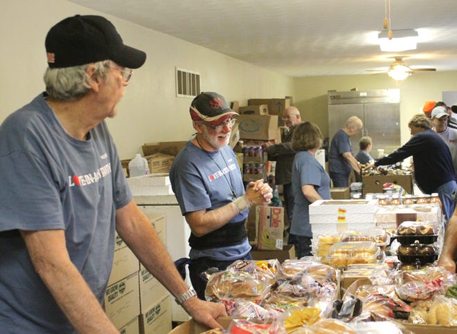 Dave Larson, left, and Wayne Miller help volunteer at the Love-In-Action food pantry at the Chillicothe 
Assembly of God Church. The food pantry recently had its 100,000th person walk through its doors.