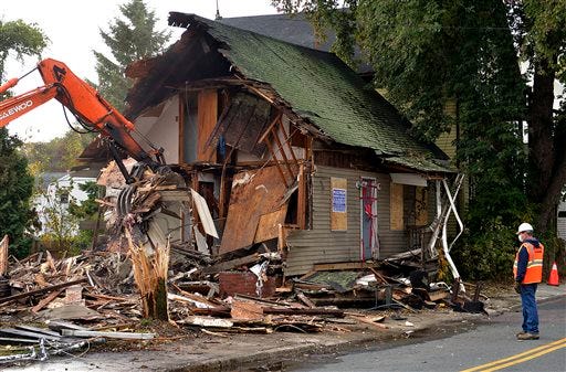 A house where the skeletal remains of three children were found last month is torn down by order of the town's Board of Health Tuesday, Oct. 21, 2014 in Blackstone, Mass.