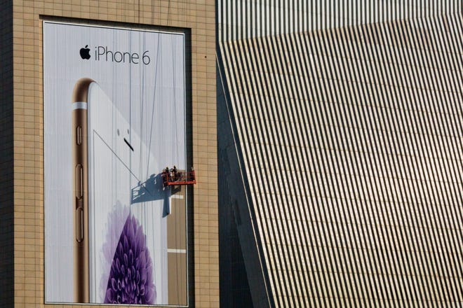Workers set up a giant advertisement for Apple's iPhone 6, which is very popular in China.