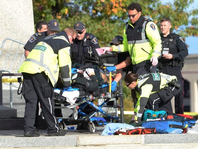 Police and paramedics tend to a soldier shot at the National Memorial near Parliament Hill in Ottawa on Wednesday Oct. 22, 2014. The soldier standing guard at the National War Memorial was shot by an unknown gunman and people reported hearing gunfire inside the halls of Parliament. Prime Minister Stephen Harper was rushed away from Parliament Hill to an undisclosed location, according to officials.