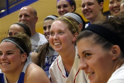 Lauren Hill, center, poses for a photo with her teammates after practicing with the NCAA college basketball team at Mount St. Joseph University in Cincinnati on Thursday, Oct. 23, 2014. Hill had made her choice. She would play basketball at the Division III school in the suburbs. Soon afterward, she started feeling bad and got tests that found an inoperable mass in her brain. (AP Photo/Tom Uhlman)