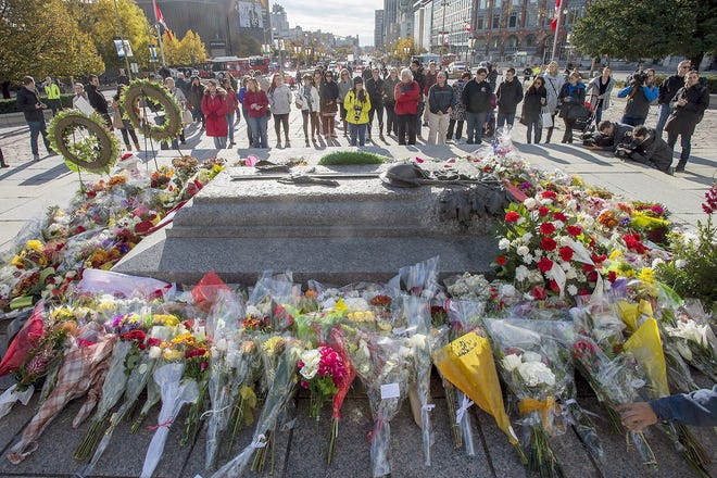 People gather around the Tomb of the Unknown Soldier at the National War Memorial in Ottawa on Friday. Canadians are mourning the loss of Cpl. Nathan Cirillo, the army reservist who was shot dead as he stood guard before the Tomb of the Unknown soldier on Wednesday. AP PHOTO/THE CANADIAN PRESS/JUSTIN TANG