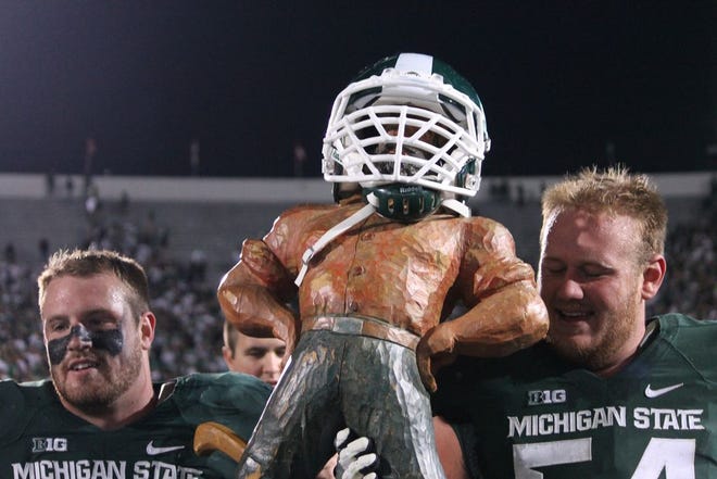Marcus Rush and Connor Kruse hold up the Paul Bunyan trophy after defeating Michigan 35-11 on Saturday night in East Lansing.