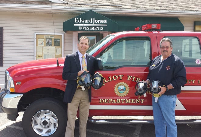 Jeffrey S. Kolod, financial adviser for Edward Jones in Eliot, Maine, presents Chief Muzeroll of the Eliot Fire Department with several Self Contained Breathing Apparatus (SCBA) masks with built-in voice amplifiers. This generous donation will help the Eliot Firefighters effectively communicate and see when fighting fires.