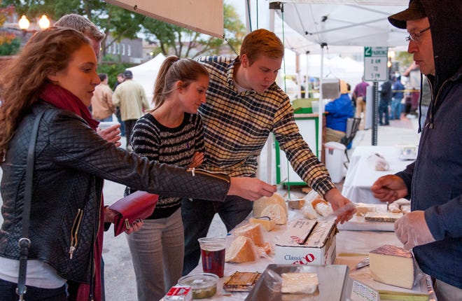 Phil Riggs (right) buys cheese from a vendor at Rockford City Market with friends Amanda Clement (from left), Collin Beck and Kelsi Rosella.
