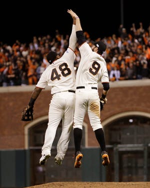 San Francisco's Pablo Sandoval, left, and Brandon Belt leap over the pitcher's mound Sunday to celebrate their win in Game 5 of the World Series. THE ASSOCIATED PRESS