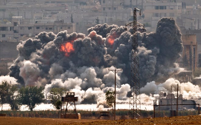 Smoke and flames rise from an Islamic State fighters' position in the town of Kobani during airstrikes by the U.S. led coalition seen from the outskirts of Suruc, near the Turkey-Syria border, Tuesday. Kobani, also known as Ayn Arab, and its surrounding areas, has been under assault by extremists of the Islamic State group since mid-September and is being defended by Kurdish fighters.