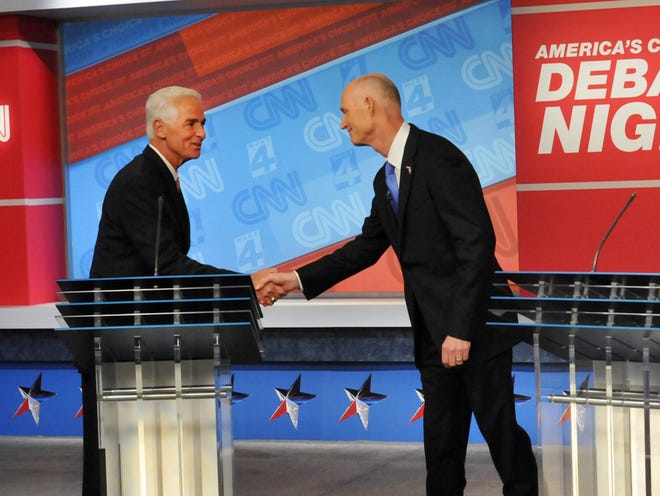 Democratic candidate Charlie Crist, left, and Republican Gov. Rick Scott shake hands before their live television debate, Tuesday, Oct. 21, 2014 hosted by WJXT-TV and CNN at the Channel 4 studios in Jacksonville.
