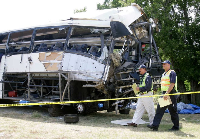 FILE - National Transportation Safety Board investigators David Rayburn, left, and Robert Accetta walk in this Aug. 10, 2008 file photo past a charter bus involved in a deadly accident early Friday that killed 17 people and left at least eight others in critical condition in Sherman, Texas. The owner of the Houston bus company who was charged after a 2008 crash has avoided prison after a federal judge sentenced him to three years of probation in a plea agreement Friday Oct. 24, 2014. (AP Photo/Matt Slocum, File)