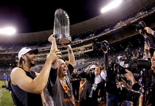 San Francisco Giants left fielder Michael Morse, left, and starting pitcher Tim Hudson hold up the trophy after their win in Game 7 of baseball's World Series against the Kansas City Royals Wednesday, Oct. 29, 2014, in Kansas City, Mo. (AP Photo/Charlie Riedel)