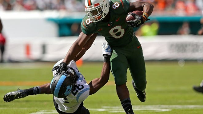 Miami’s Duke Johnson runs over a North Carolina defender during the Hurricanes’ rout of the Tar Heels on Saturday in Miami Gardens. (Photo by Mike Ehrmann/Getty Images)