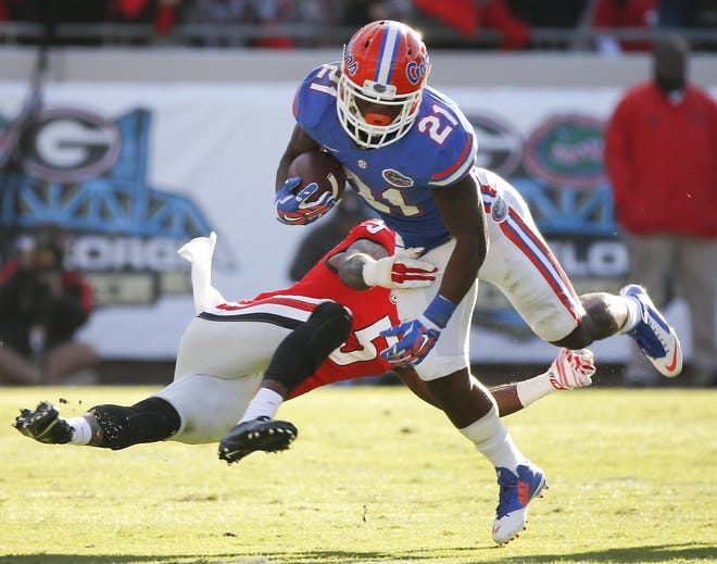 Florida running back Kelvin Taylor (21) is brought down by Georgia cornerback Damian Swann (5) during the first half of an NCAA college football game in Jacksonville, Fla., Saturday, Nov. 1, 2014. (AP Photo/Stephen B. Morton)
