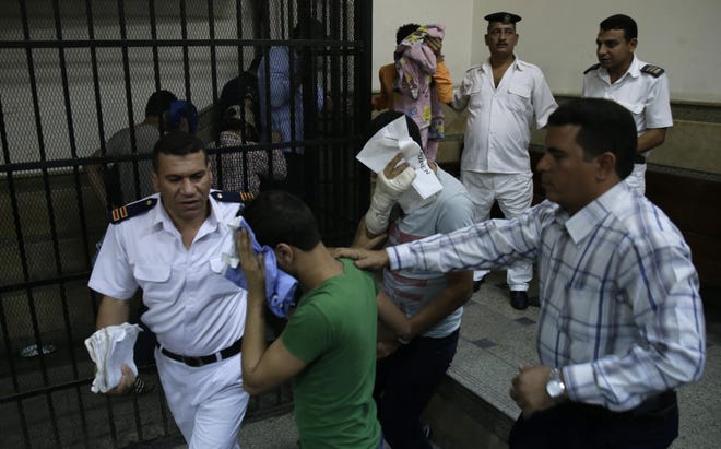 Eight Egyptian men convicted for "inciting debauchery" following their appearance in a video of an alleged same-sex wedding party on a Nile boat cover their faces as they leave the defendant's cage in a courtroom in Cairo, Egypt, Saturday, Nov. 1, 2014. Saturday's verdict that sentenced each of them to three years in prison is the latest in a crackdown by authorities against gays, atheists, liberal and pro-democracy activists and violators of a draconian law on street protests. Consensual same-sex relations are not explicitly prohibited, but other laws have been used to imprison gay men in recent years. Egypt's crackdown is taking place as the country of nearly 90 million people appears to be steadily moving to the right, with jingoism and xenophobia dominating the media. (AP Photo/Hassan Ammar)