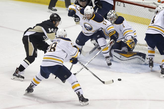 Pittsburgh Penguins' Chris Kunitz (14) gets between Buffalo Sabres' Zemgus Girgensons (28) and Torrey Mitchell (17) to score a goal on goalie Jhonas Enroth (1) in the first period of an NHL hockey game, Saturday, Nov. 1, 2014 in Pittsburgh. (AP Photo/Keith Srakocic)