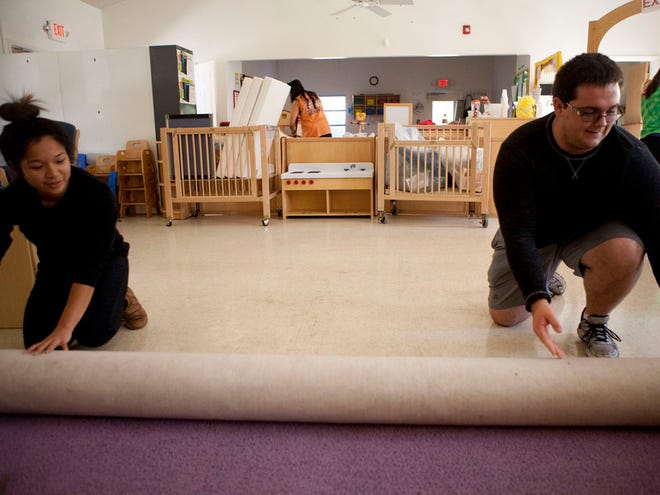 University of Florida students Thanh Nguyen and Eric Mulligan roll up an old rug at Redlands Christian Migrant Association Center Sunday, November 2, 2014 in Kendrick, Fla. The Alpha Phi Omega service fraternity is helping renovate the child care center for early next year when migrant workers come back to Ocala for the start of blueberry season.