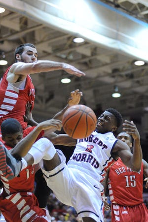 Kavon Stewart (3) of Robert Morris draws a foul as he is defended by Ronnie Drinnon (40) and Ben Millaud-Meunier (11) of St. Francis. Photo by Dave Miller for The Times