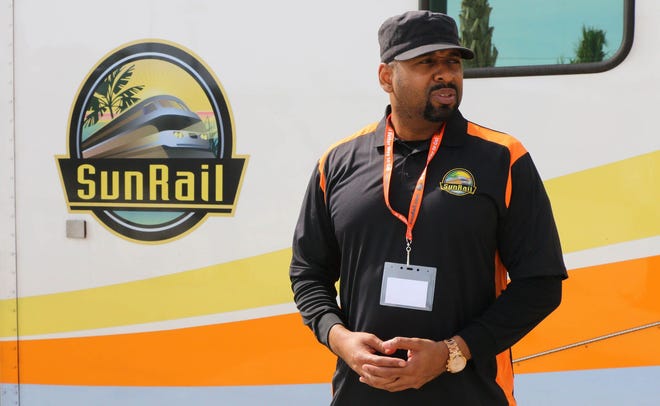 Etienne Seales, an ambassador for the SunRail commuter train, helps riders at the DeBary station on Wednesday.