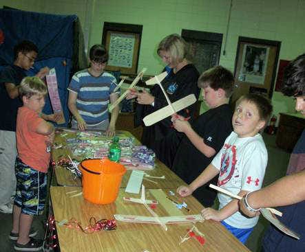 Courtesy of Tracy Robinson STEM students and dvisor Inga Cashon help participants build wooden, rubber band powered airplanes.