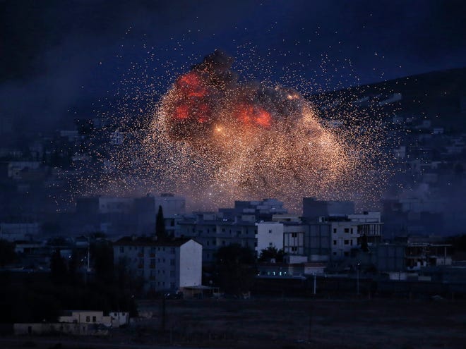 In this Oct. 20, 2014 file photo, thick smoke and flames from an airstrike by the U.S.-led coalition rise in Kobani, Syria, are seen from a hilltop on the outskirts of Suruc, at the Turkey-Syria border.