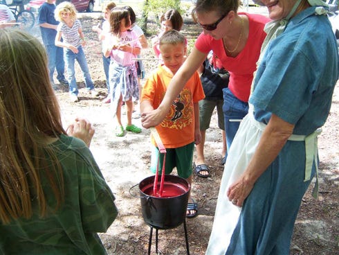 Pioneer Day activities include candle-dipping shown here during a previous year’s event.