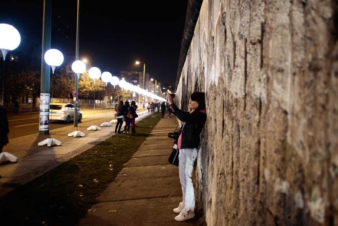 Markus Schreiber/The Associated PressA woman takes a photo of balloons of the art project "Lichtgrenze 2014" (lit. "lightborder 2014") at the wall memorial site Bernauer Strasse in Berlin, Germany.