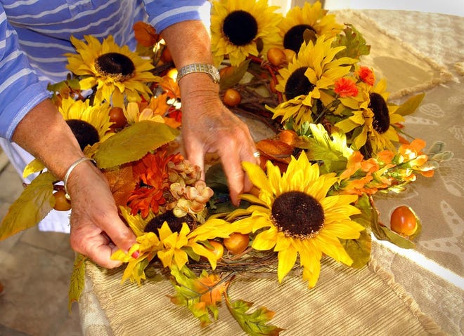A wreath can add a touch of seasonal cheer after the flowers have departed. The practiced hands of Jean Ashworth plump up the decorations of a fall wreath. She has been making wreaths for more than 30 years. Laura McLean/Standard-Times special