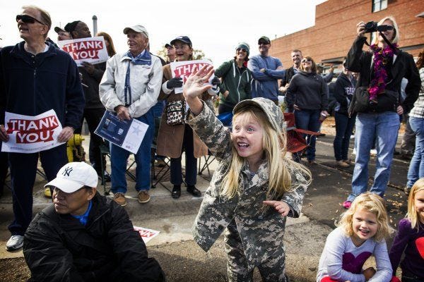 Above: Azalea Strifler, 5, waves to her dad as he passes by in the Veterans Day parade Saturday in downtown Fayetteville.Left: Parade attendees hold up 'thank you' signs as the 82nd Airborne Division marches. See more photos at fayobserver.com.