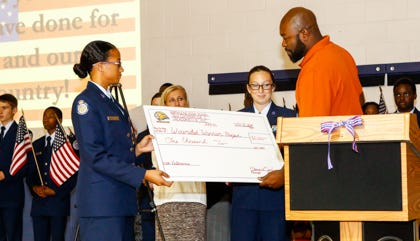 Northside High School Air Force JROTC Cadets Asha Stewart and Samantha Mumford present Bo McCalister with a check for Wounded Warriors Project from the money raised selling flags in honor of Veterans Day at a ceremony held on Monday at Northside High School.